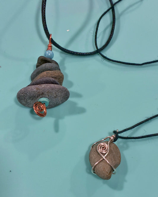 Two stone pendants on black cords against a light blue background